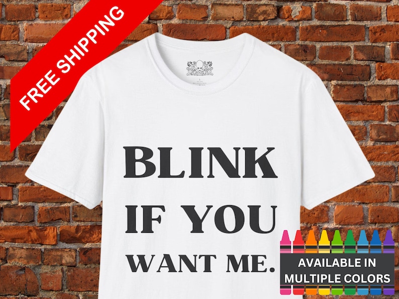 May include: White t-shirt with black text that reads "Blink if you want me."  The text is in a bold, sans-serif font.  The shirt is available in multiple colors.