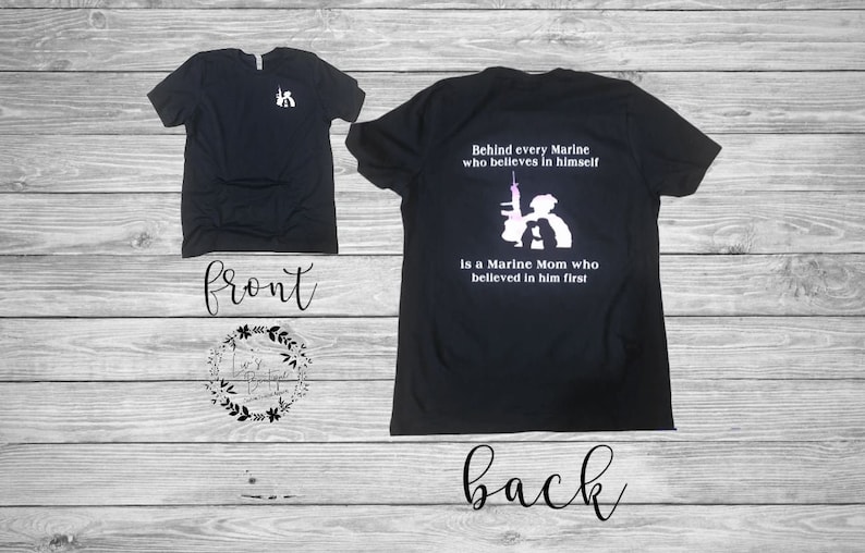 Peut inclure: T-shirt noir avec un graphique blanc au dos qui dit "Behind every Marine who believes in himself is a Marine Mom who believed in him first".