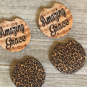 May include: Four round coasters, two with a leopard print design and two with a musical note background and the text "Amazing Grace".