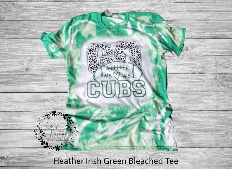K&ouml;nnte beinhalten: Gr&uuml;n-wei&szlig;es Batik-T-Shirt mit einem wei&szlig;en Football-Motiv und dem Text "Go Cubs #5 #6" in Schwarz.