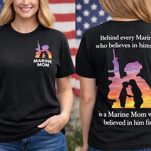 Marine Mom shirt on a black tee showing front left‑chest crest with Marine and mom silhouette in sunset colors, and back design with quote ‘Behind every Marine who believes in himself is a Marine Mom who believed in him first,’ modeled outdoors with American flag background.