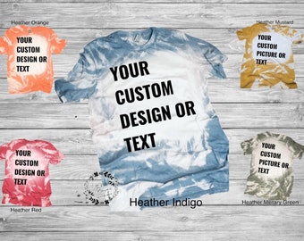 May include: Five tie-dye t-shirts in different colours with the text "YOUR CUSTOM DESIGN OR TEXT" printed on each. The colours are heather orange, heather indigo, heather red, heather mustard, and heather military green.