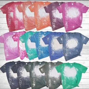 May include: A collection of 14 t-shirts in various heather colors, each with a bleach-splattered design. The colors include red, cardinal red, bronze, orange, maroon, radiant orchard, berry,  navy, dark heather,  sealoam, sapphire, royal, indigo, forest green, military green, and Irish green.