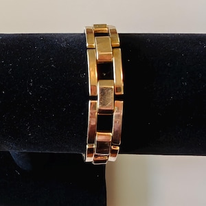 May include: A gold-toned bracelet with a chain link design. The bracelet is made of metal and has a polished finish.