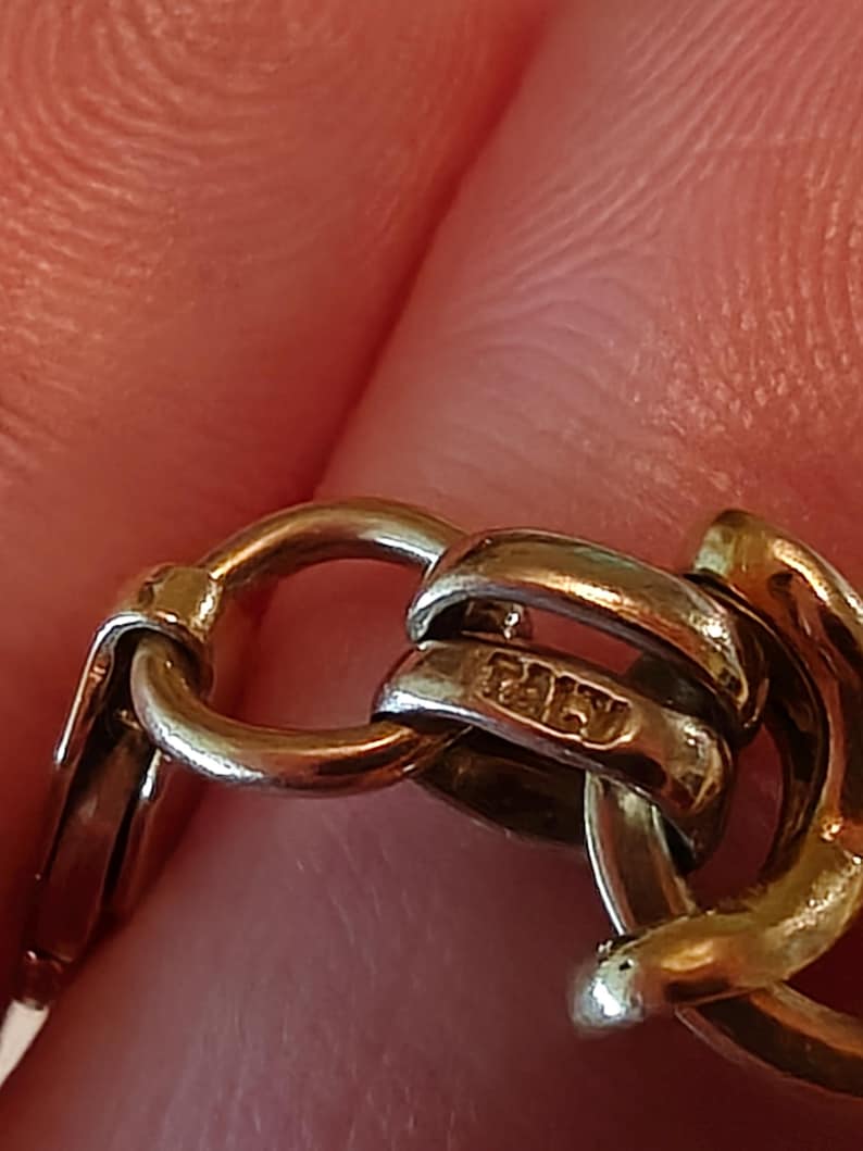 May include: Close-up of a gold chain with a hallmark that reads "ITALY".