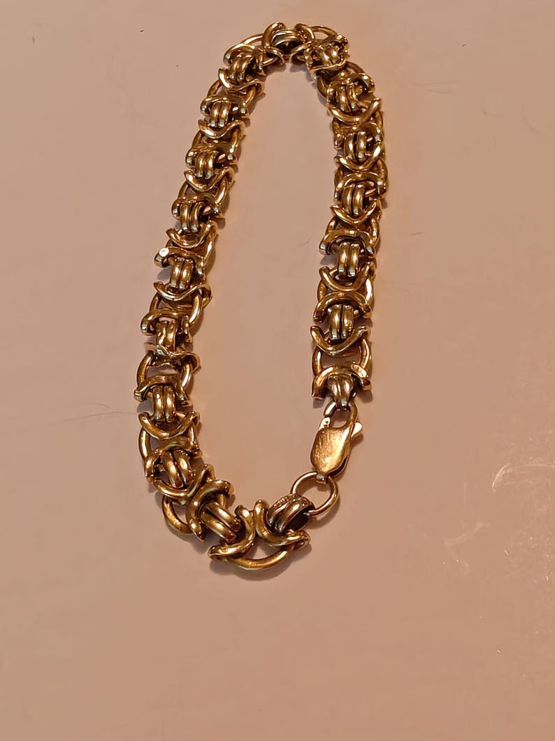 May include: A gold chain bracelet with a Byzantine style design. The bracelet has a clasp closure.
