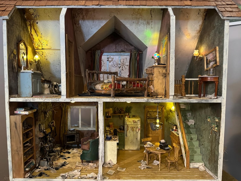 May include: A dollhouse with three rooms, a bedroom, a kitchen, and a living room. The dollhouse is made of wood and has a white paint finish. The rooms are furnished with miniature furniture, including a bed, a stove, a table, and chairs. The dollhouse is decorated with miniature accessories, such as a lamp, a rug, and a picture.
