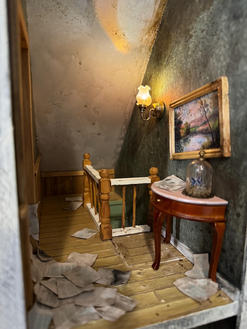 May include: A miniature dollhouse room with a wooden staircase, a small table with a glass dome, and a framed picture on the wall. The room is decorated with a vintage aesthetic, with a worn wooden floor and a dusty, textured wall.