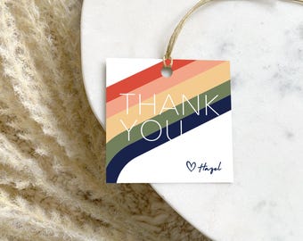 May include: A white thank you tag with a rainbow design and the text "Thank You" in white. The tag has a heart and the name "Hazel" written in black.