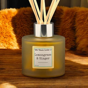 May include: A frosted glass diffuser bottle with a silver cap and wooden reeds. The label reads "Little Rituals Candle Co. Lemongrass & Ginger 100 ml."