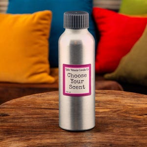 May include: A silver metal bottle with a black lid. The bottle has a pink label that says "Little Rituals Candle Co. Choose Your Scent 100 ml".