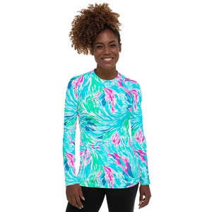 May include: A long-sleeved shirt with a colorful abstract pattern in shades of blue, pink, and green. The shirt has a crew neck and a fitted silhouette.