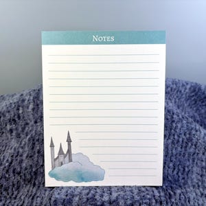May include: A lined notepad with the word "NOTES" at the top. The notepad features a watercolor illustration of a gray castle on a blue cloud in the bottom corner. The notepad is white with horizontal lines.