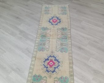 Puede incluir: Una alfombra de pasillo vintage con fondo crema y un patrón repetitivo de motivos florales azules, verdes y rosas. La alfombra tiene un aspecto desgastado y es perfecta para añadir un toque de estilo bohemio a cualquier habitación.