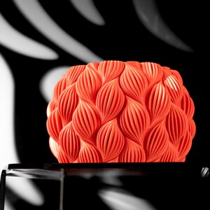 May include: A bright orange, 3D printed, decorative object with a textured, leaf-like pattern.