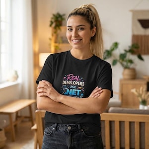 May include: Black t-shirt with the text "Real Developers Use .NET" in a colorful design. The shirt is a classic crew neck style and is made of a soft material. The design features a computer icon.