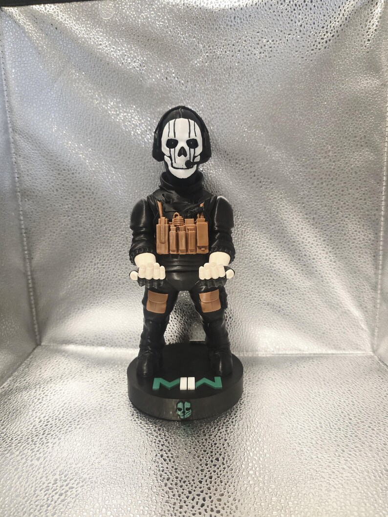 K&ouml;nnte beinhalten: Figur eines Charakters aus dem Videospiel Call of Duty: Modern Warfare. Die Figur tr&auml;gt eine schwarze taktische Kleidung mit einer Totenkopfmaske und einen Sockel mit der Aufschrift "MWII". Die Figur ist etwa 15 cm gro&szlig;.