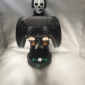 K&ouml;nnte beinhalten: Schwarze Gaming-Controller-Figur mit einem sch&auml;delgesichtigen Kopf und einem schwarzen Sockel. Der Controller hat Tasten und ein Steuerkreuz. Der Sockel tr&auml;gt die Buchstaben "MWII" in Wei&szlig; und Gr&uuml;n. Die Figur ist ein Sammlerst&uuml;ck.