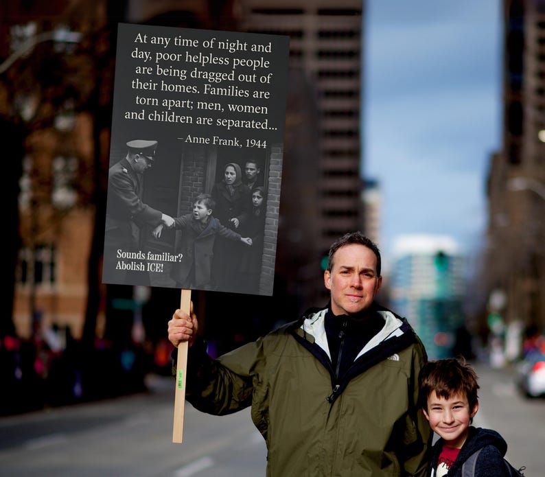 May include: A sign held by a person with the text: "At any time of night and day, poor helpless people are being dragged out of their homes. Families are torn apart; men, women and children are separated... - Anne Frank, 1944. Sounds familiar? Abolish ICE!"