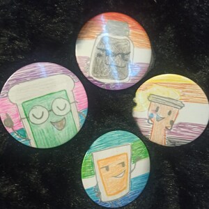 Puede incluir: Cuatro botones redondos con dibujos animados. Los botones presentan fondos coloridos con dibujos de una botella, un vaso de precipitados, una taza de café y una caja de zumo. Los dibujos tienen caras sonrientes y están delineados en negro.