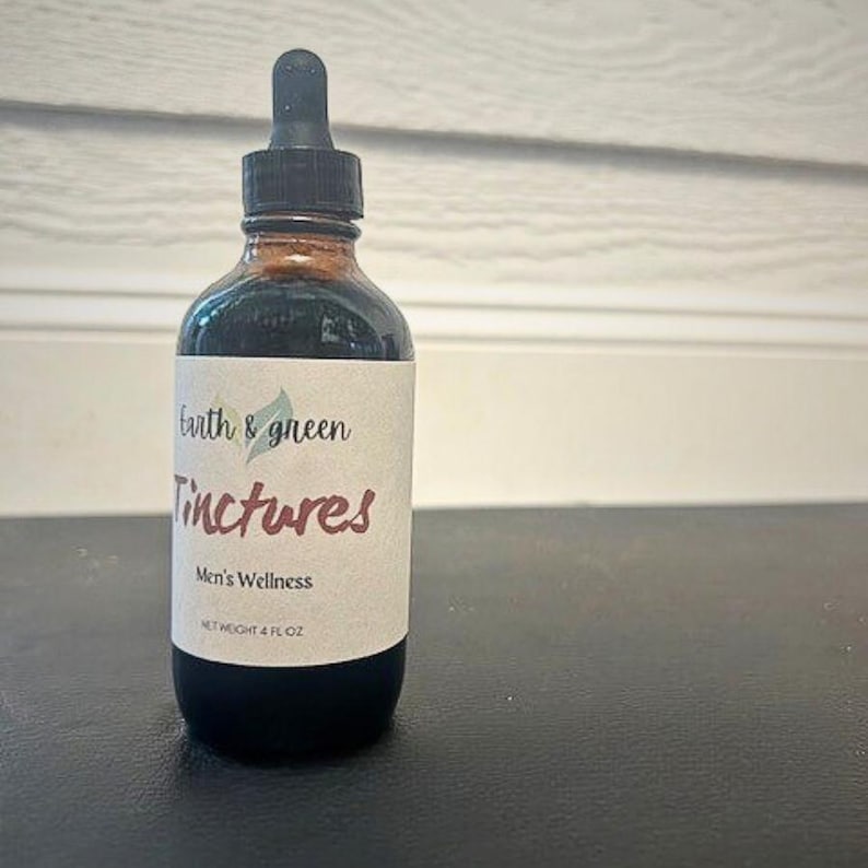 May include: A brown glass bottle with a black dropper, labelled "Earth & Green Tinctures, Men's Wellness, Net Weight 4 fl oz." The bottle contains a dark liquid. The label is white with brown and green text.