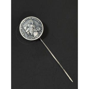 May include: A silver-toned pin with a circular emblem featuring the text "EX-STUDENTS ASSN. TEXAS TECH CENTURY CLUB." The emblem depicts a figure and architectural elements. The pin is set against a dark background.