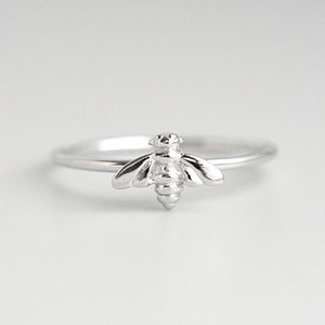 May include: A silver ring with a bee design.