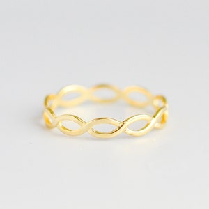 May include: A gold-colored ring with a delicate, interwoven design. The ring is made of a thin metal and has a simple, elegant style.