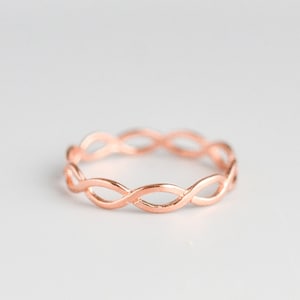 Op de afbeelding: Een ring van roségoud met een gevlochten ontwerp.