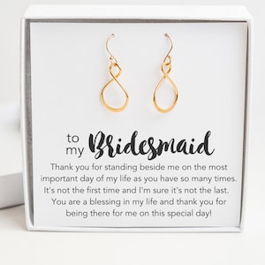 May include: A white gift box with a gold infinity symbol earring set inside. The box has a message that reads "to my Bridesmaid. Thank you for standing beside me on the most important day of my life as you have so many times. It's not the first time and I'm sure it's not the last. You are a blessing in my life and thank you for being there for me on this special day!"