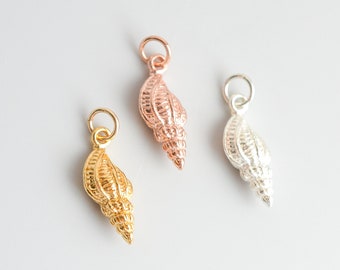 May include: Three gold, rose gold, and silver shell charms. The charms are detailed and have a textured surface.
