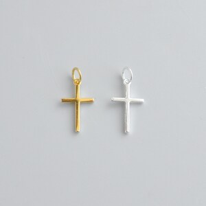 Sterling silver and gold cross charms lying flat on a white background, highlighting the smooth surface and precise 16x9.5mm shape.