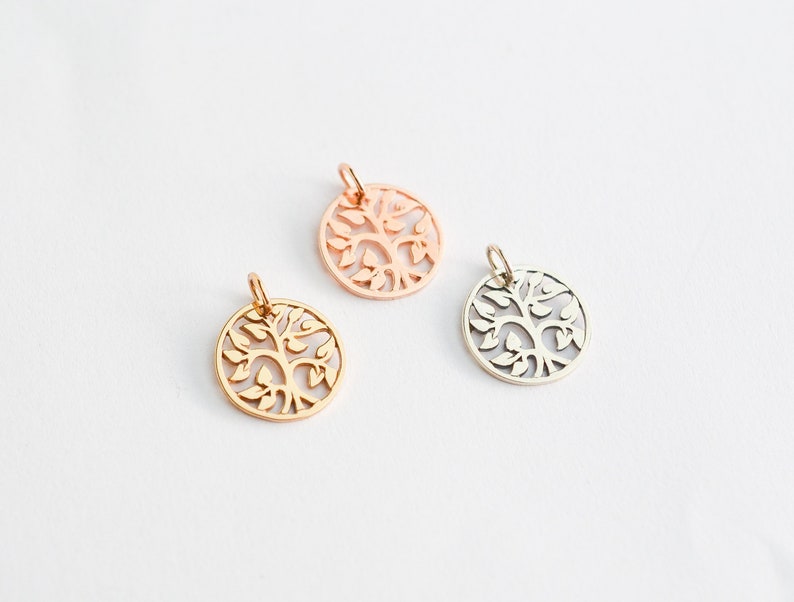 May include: Three circular pendants with a tree of life design. One is gold, one is rose gold, and one is silver. Each pendant has a small loop at the top for a chain.