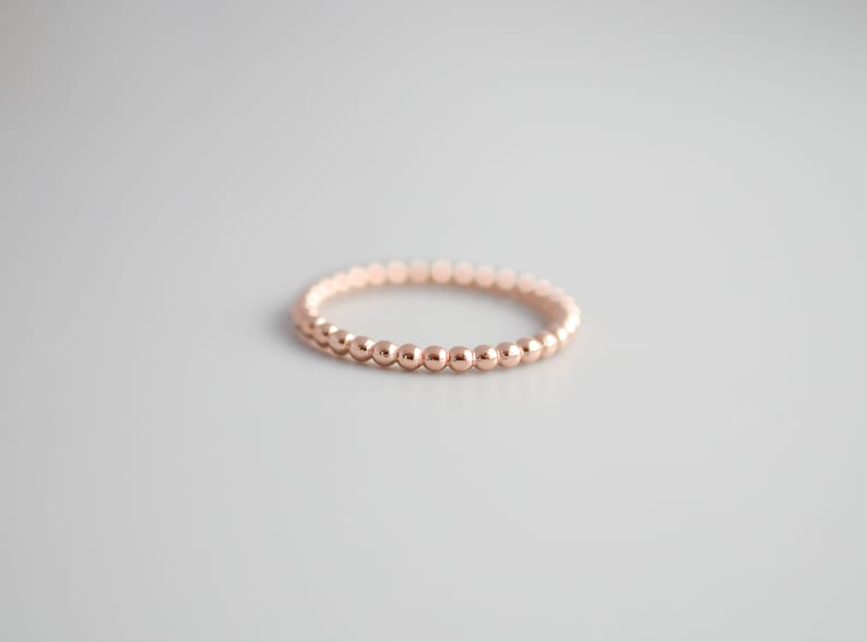 K&ouml;nnte beinhalten: Ein zarter Ring aus Ros&eacute;gold, der aus kleinen, runden Perlen besteht.