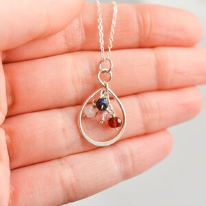 May include: A silver necklace with a teardrop-shaped pendant. The pendant is filled with small pink, red, and blue gemstones.