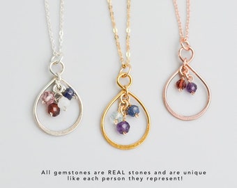 May include: Three delicate necklaces with teardrop-shaped pendants featuring small gemstones. The pendants are made of silver, gold, and rose gold. Each pendant has a different combination of gemstones, including amethyst, aquamarine, garnet, sapphire, and moonstone.