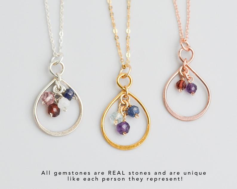 May include: Three delicate necklaces with teardrop-shaped pendants featuring small gemstones. The pendants are made of silver, gold, and rose gold. Each pendant has a different combination of gemstones, including amethyst, aquamarine, garnet, sapphire, and moonstone.