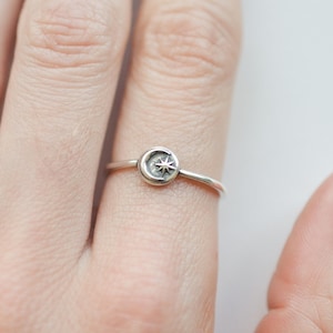 May include: A silver ring with a crescent moon and star design.