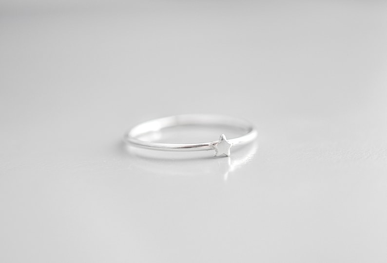 May include: A simple silver ring with a small star design.