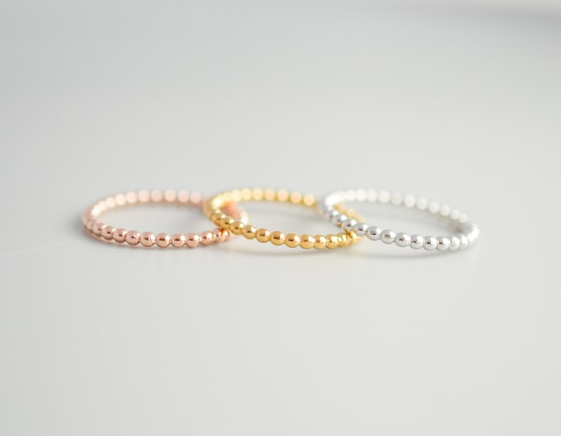 K&ouml;nnte beinhalten: Drei Perlenringe in verschiedenen Farben: Ros&eacute;gold, Gold und Silber. Die Ringe sind &uuml;bereinander gestapelt.