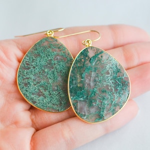 May include: A pair of gold-tone dangle earrings with green agate stone drops. The stones have a unique, marbled pattern.
