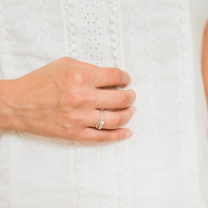 May include: A close-up of a hand wearing a delicate silver ring with a small star design.