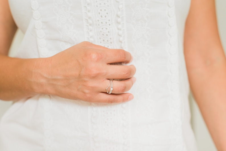 May include: A close-up of a hand wearing a delicate silver ring with a small star design.