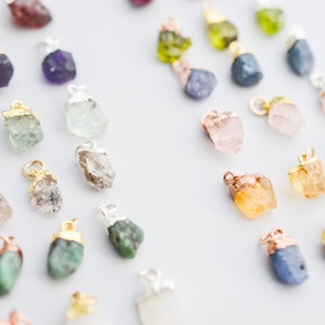 Puede incluir: Surtido de colgantes de piedras preciosas en bruto en varios colores, incluyendo amatista, aguamarina, esmeralda, citrino, cuarzo rosa y zafiro. Cada colgante est&aacute; unido a una cadena de plata u oro.