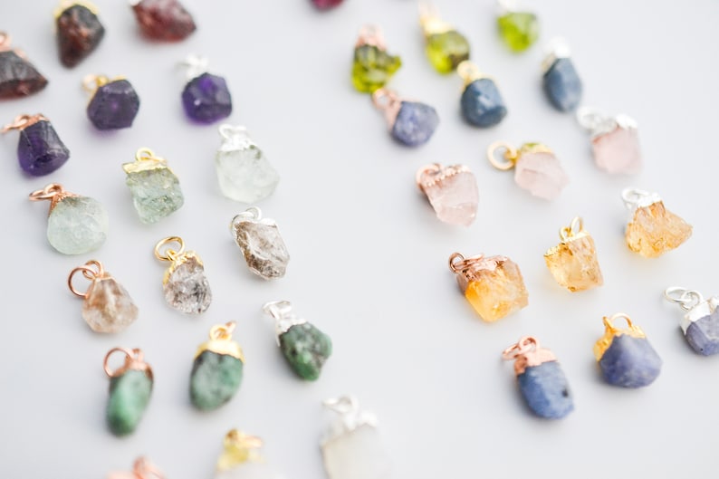 Puede incluir: Surtido de colgantes de piedras preciosas en bruto en varios colores, incluyendo amatista, aguamarina, esmeralda, citrino, cuarzo rosa y zafiro. Cada colgante est&aacute; unido a una cadena de plata u oro.