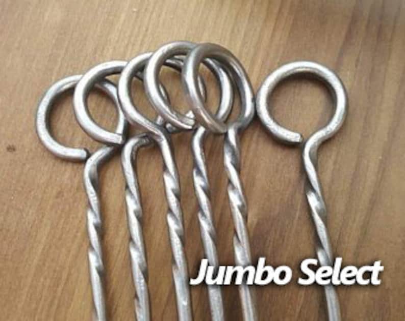 May include: Six silver metal skewers with twisted handles and a loop at the top. The skewers are labeled "Jumbo Select".