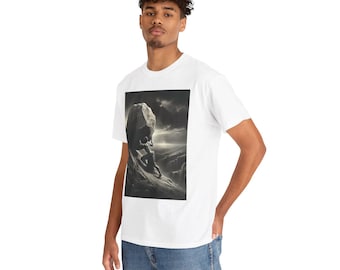 Puede incluir: Una camiseta blanca de manga corta con un estampado gráfico rectangular en el pecho. El estampado muestra una escena monocromática de una figura empujando una gran roca por una ladera montañosa empinada y rocosa bajo un cielo nublado.