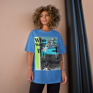 Peut inclure: Un t-shirt bleu avec un graphisme d'un joueur de football américain attrapant un ballon. Le t-shirt porte l'inscription "Who Wants It" en blanc et vert. L'image est une illustration stylisée d'un match de football.