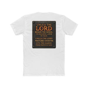 May include: A white short-sleeved t-shirt featuring a rectangular black graphic on the back. The graphic displays the text: UNLESS THE LORD BUILDS THE HOUSE, THE BUILDERS LABOR IN VAIN. UNLESS THE LORD WATCHES OVER THE CITY, THE GUARDS STAND WATCH IN VAIN.