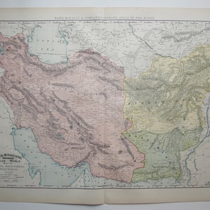 May include: A vintage map of Persia, Afghanistan, Baluchistan, and the surrounding areas. The map is printed in shades of pink, green, and yellow, with black lines for borders and rivers. The map is titled "Rand McNally & Company's Indexed Atlas of the World."